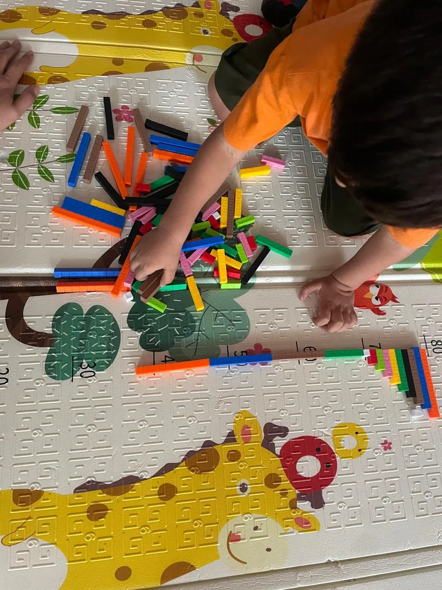 Manos de un niño ordenando crayones sobre un tapete de juego